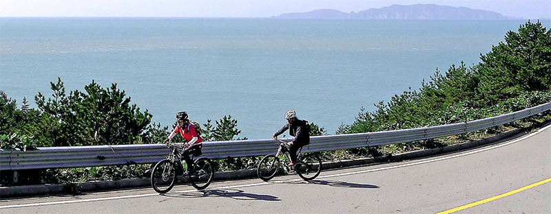자전거를 타고 해안도로를 가는 여행자들